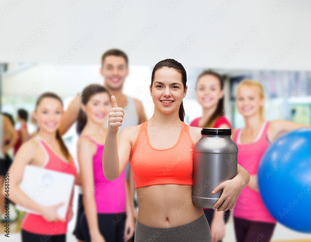 teenage girl with jar of protein showing thumbs up teenage girl with jar of protein showing thumbs up
