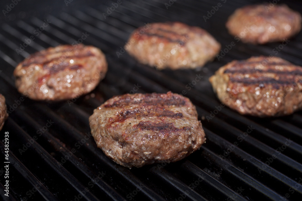 Hamburger patties cooking on a grill. Hamburger patties cooking on a grill.