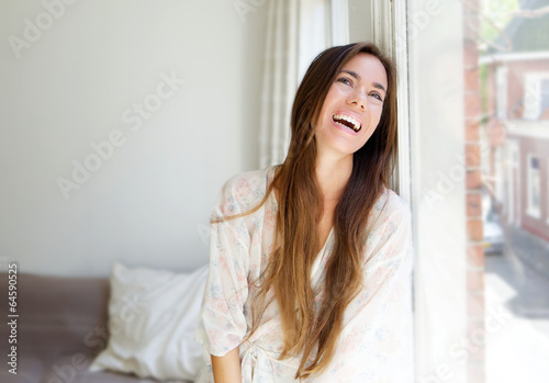 Smiling young woman sitting next to window © mimagephotos