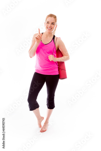 Young woman carrying exercise mat smiling and pointing up