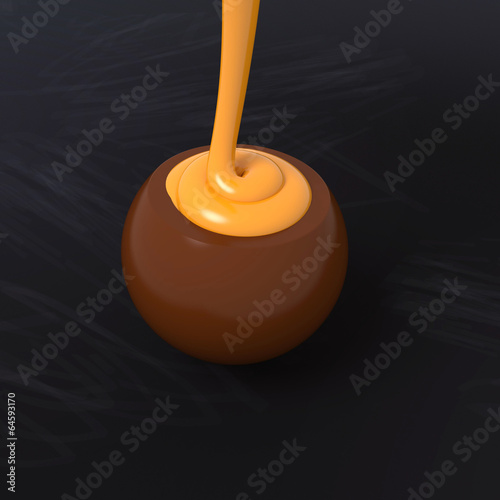 Milk chocolate praline with orange cream filling on blackboard