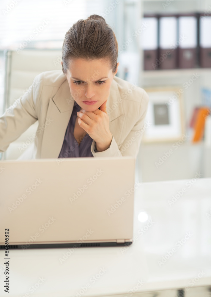 Thoughtful business woman working on laptop in office Thoughtful business woman working on laptop in office