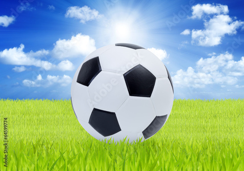Soccer ball on green grass with blue sky background