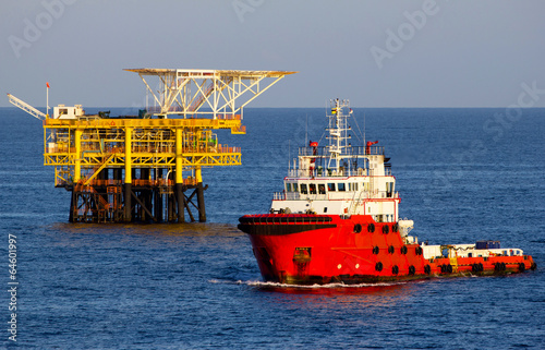Canvas Print Offshore drilling rig and supply vessel at sunset