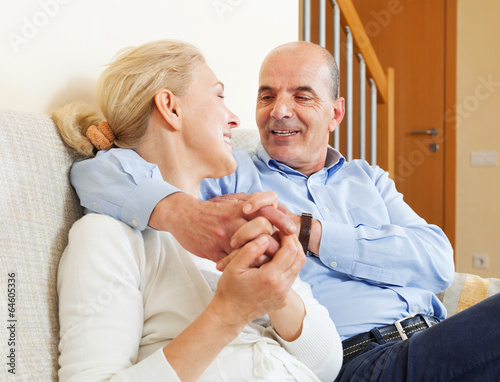 joyful elderly couple together on sofa in home interior