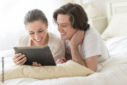 Couple Using Digital Tablet In Bed