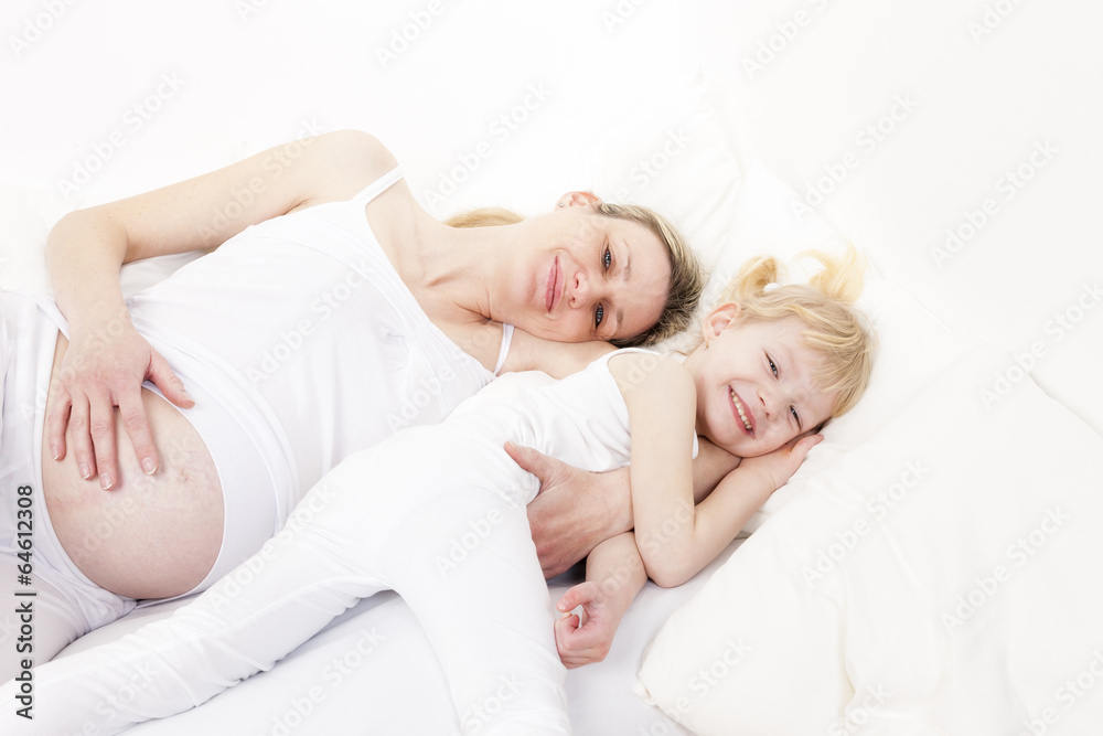 little girl with her pregnant mother resting in bed little girl with her pregnant mother resting in bed