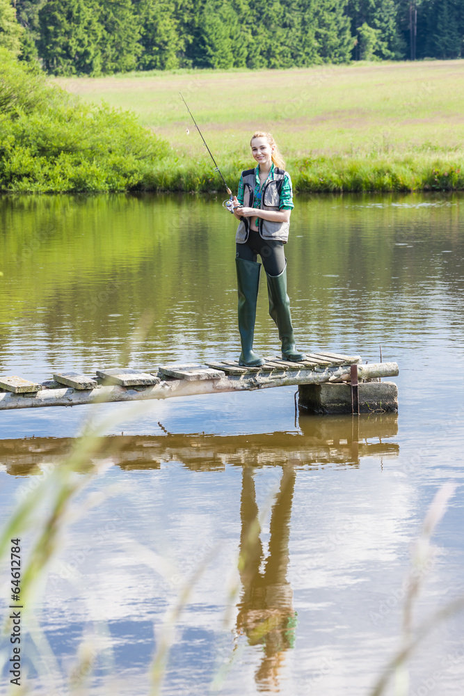 young woman fishing on pier at pond