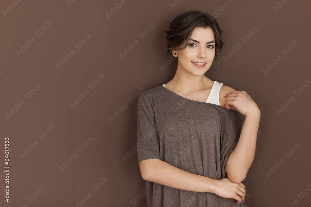 Obraz premium Portret uśmiechnięta kobieta na brązowej ścianie