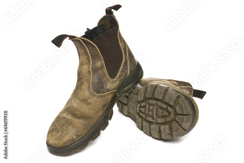 Old pair of dirty working boots isolated on white background.