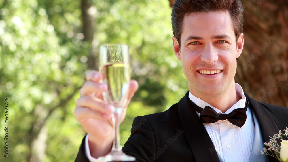 Happy groom smiling at camera and toasting with champagne Happy groom smiling at camera and toasting with champagne