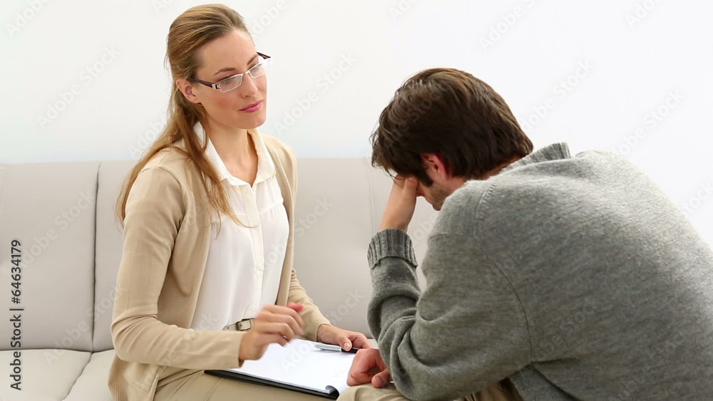 Young man sitting on sofa talking to his therapist Young man sitting on sofa talking to his therapist