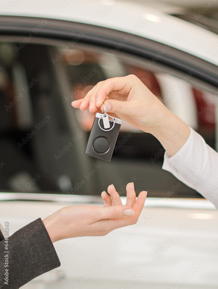 Female hand getting modern car key on a car background