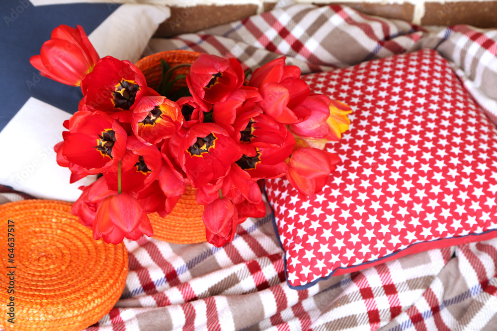 Colorful tulips with plaid and pillows on bright background