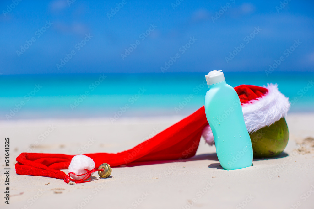 Suncream and Santa Hat on coconut at white exotic beach Suncream and Santa Hat on coconut at white exotic beach