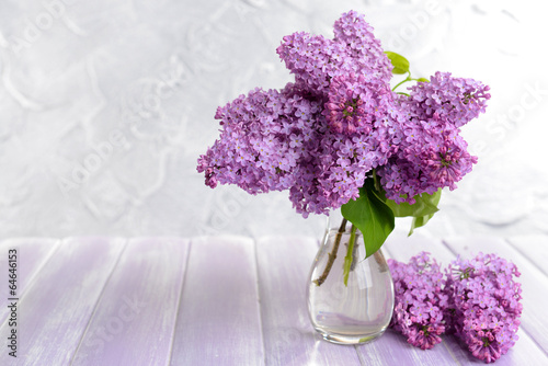 Beautiful lilac flowers in vase on table on light background photo