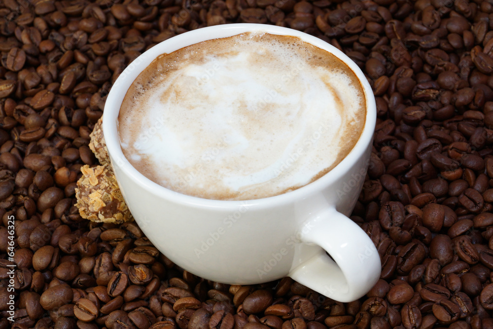cup of coffee and candies on a coffee beans background