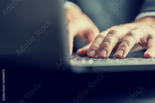 Businessman typing on a laptop computer photo