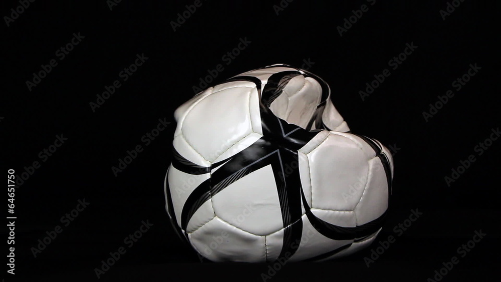 Soccer ball is deflating on a black background, close up Soccer ball is deflating on a black background, close up
