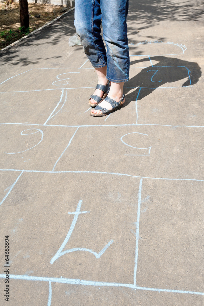 girl playing in hopscotch on urban alley