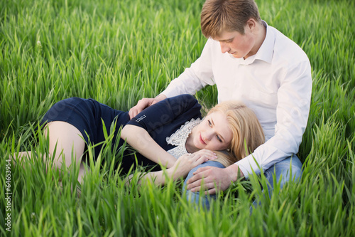 young couple sitting on green grass