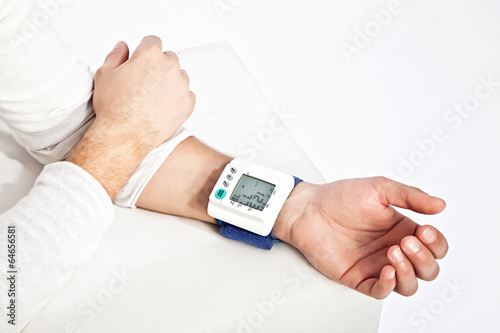 Photo of young man’s hand measuring his blood pressure photo