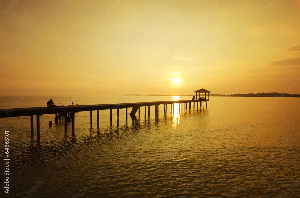 a man sitting on the bridge alone during sunset