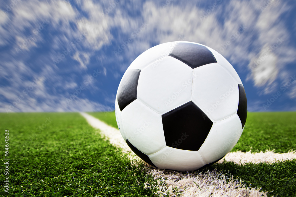 Fototapeta premium soccer ball on grass field with blue sky