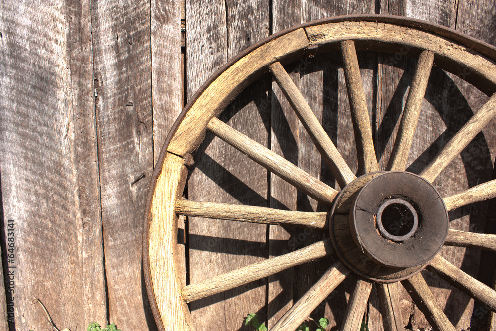 Wooden wheel leaning against barn