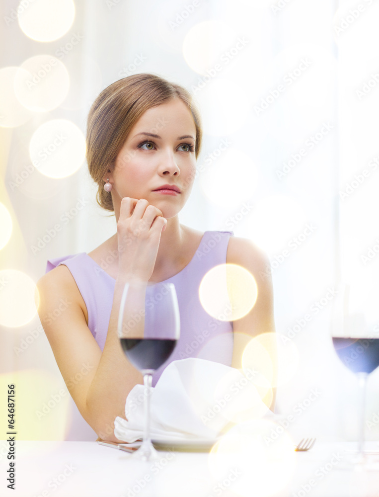 upset woman with glass of whine waiting for date