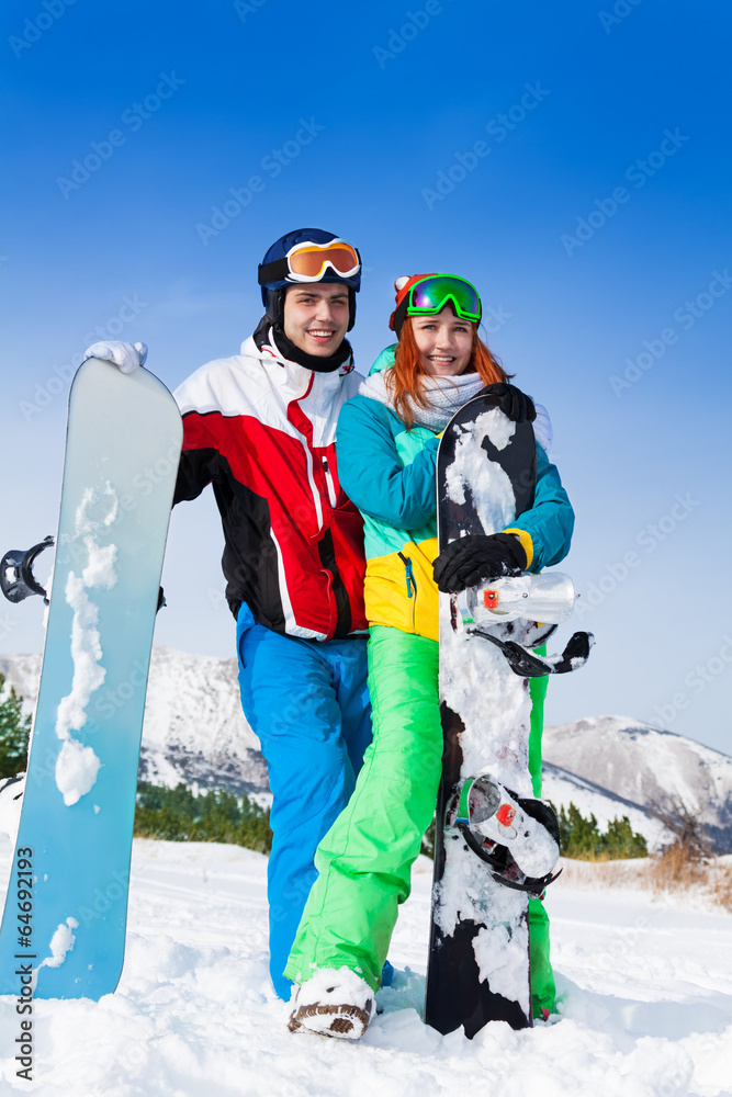 Standing smiling snowboarders with boards