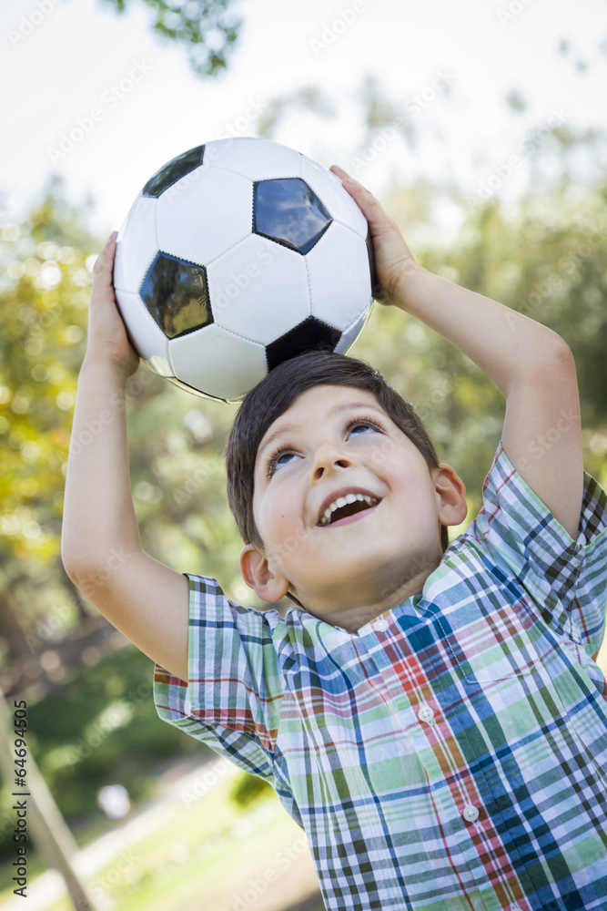 Naklejka premium Cute Young Boy Playing with Soccer Ball in Park