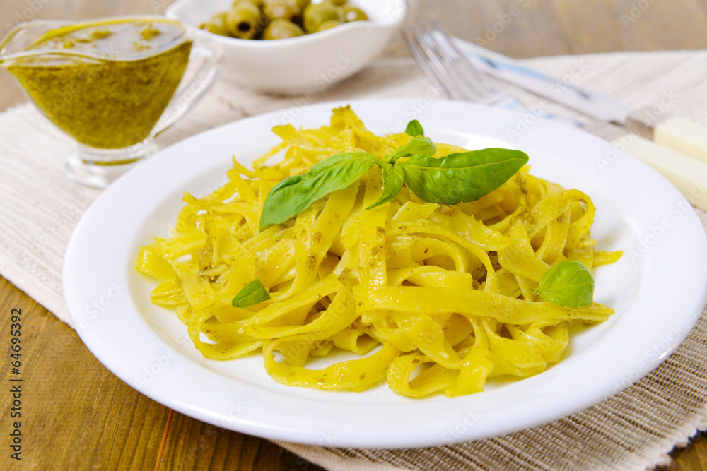 Delicious pasta with pesto on plate on table close-up