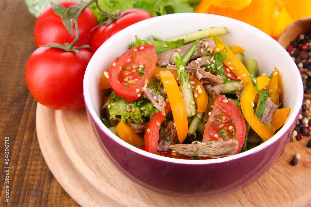 Beef salad in bowl with vegetables and spices on wooden table Beef salad in bowl with vegetables and spices on wooden table