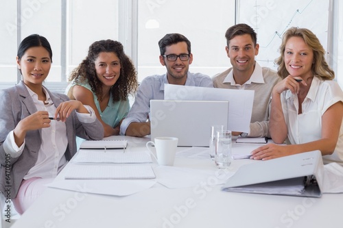 Casual business team having a meeting smiling at camera