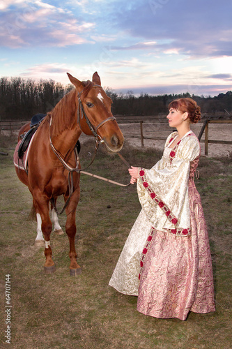 beautiful girl in antique dress next to a horse
