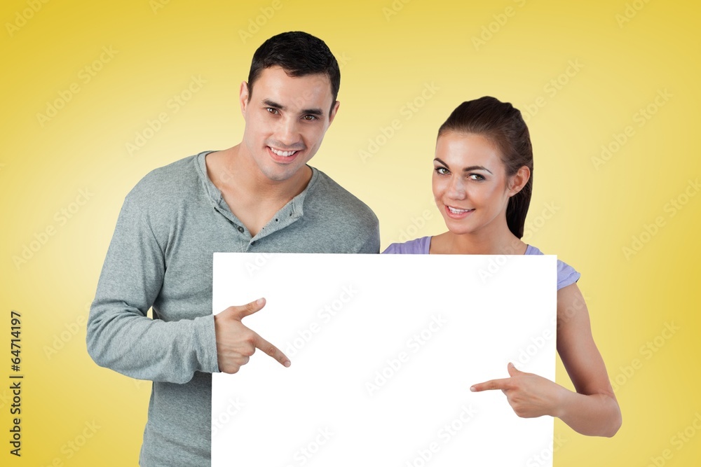 Composite image of attractive young couple showing card Composite image of attractive young couple showing card