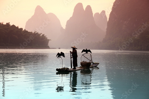 YANGSHUO - JUNE 18: Chinese man fishing with cormorants birds in