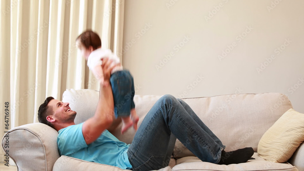 Father playing with his baby boy on the couch Father playing with his baby boy on the couch
