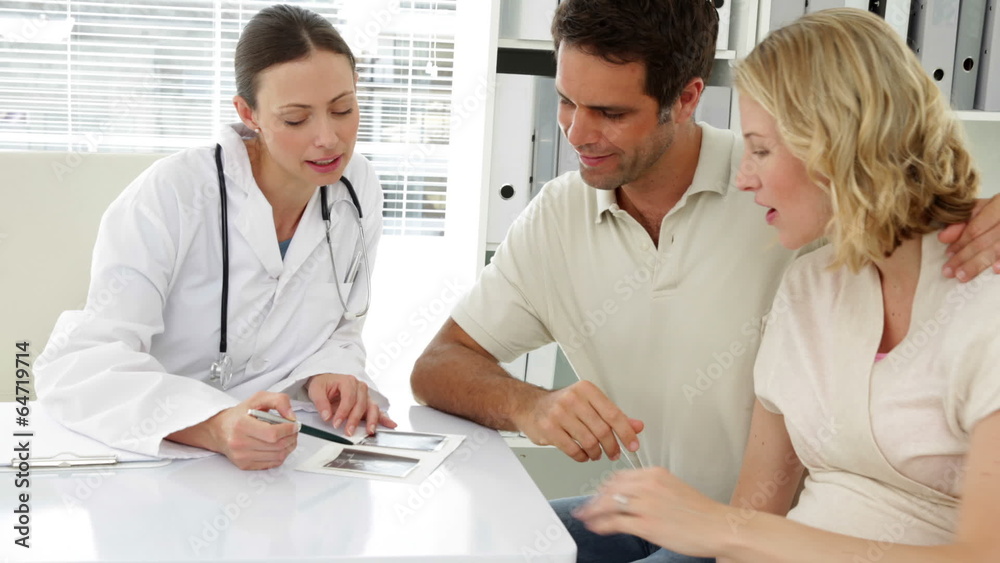 Doctor talking with expectant parents showing them sonagram Doctor talking with expectant parents showing them sonagram