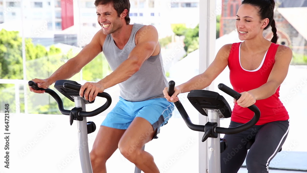 Fit couple working out on exercise bikes Fit couple working out on exercise bikes