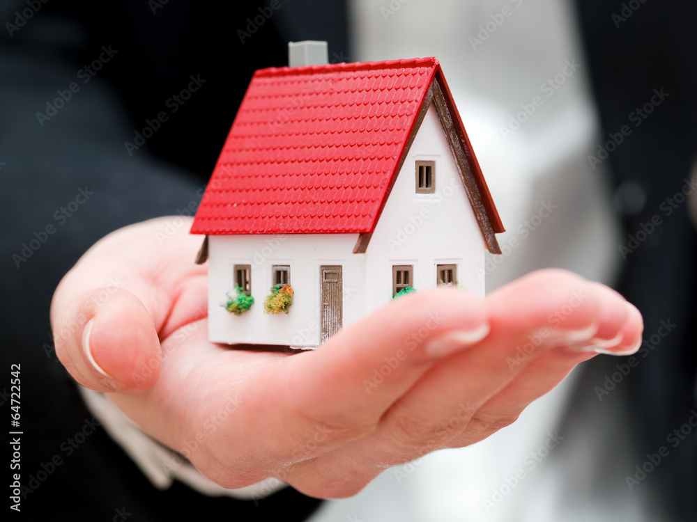 A real estate agent holding a small new house in her hands A real estate agent holding a small new house in her hands