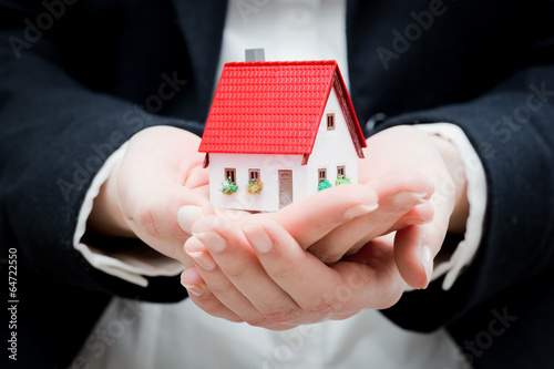A real estate agent holding a small new house in her hands