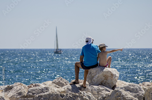 Padre con hijo sentados frente al mar