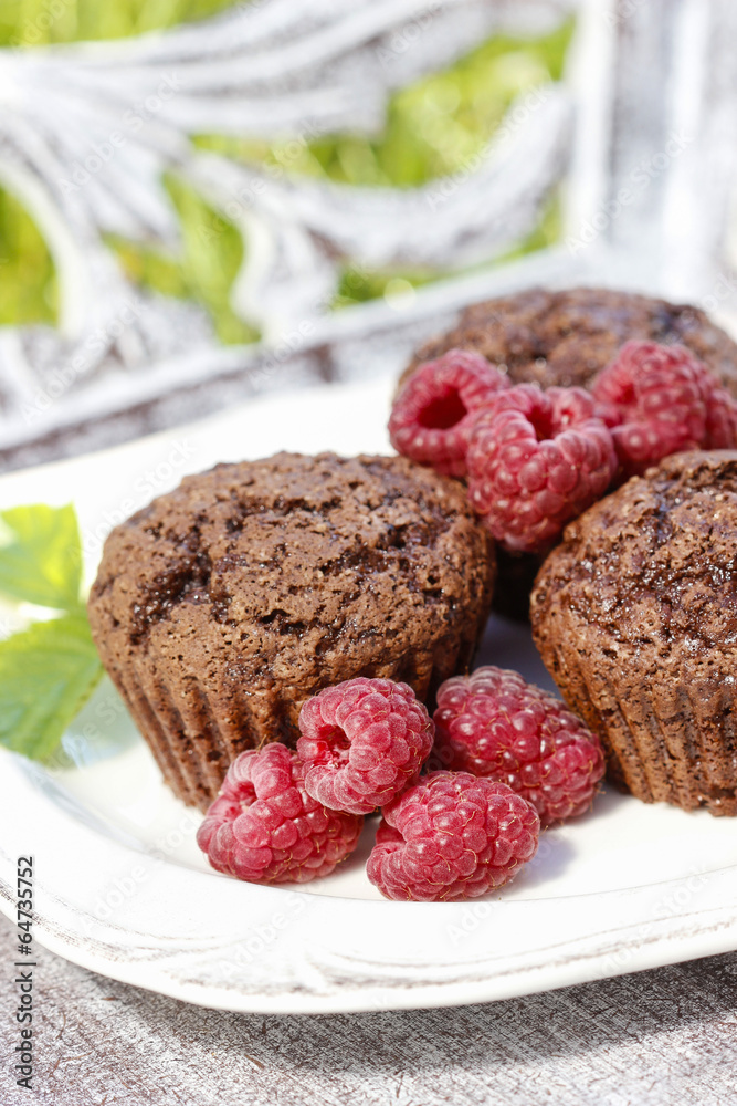Muffins with fresh raspberries on wooden tray in the garden Muffins with fresh raspberries on wooden tray in the garden