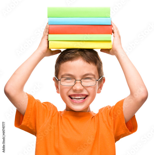 Little boy is holding a pile of books