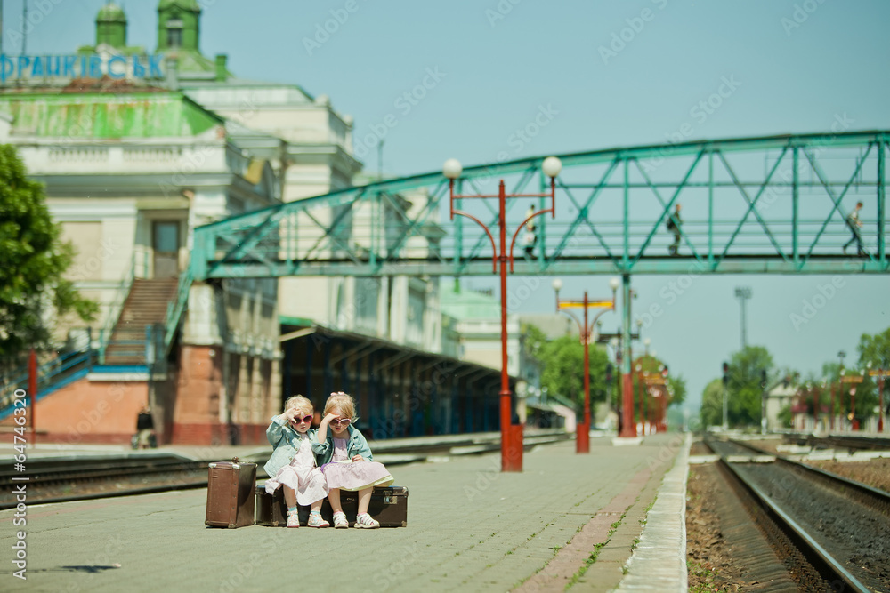 Vintage looking picture of small girls with luggage at the railw