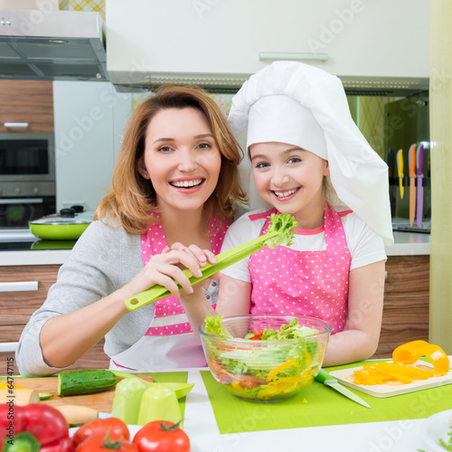 Happy mother and daughter cooking a salad.