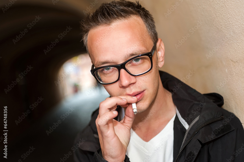 Portrait of young man smoking a cigarette in the street. Portrait of young man smoking a cigarette in the street.