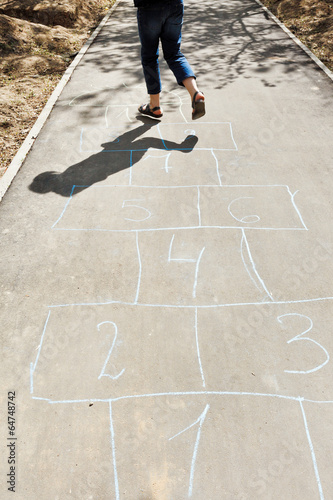 girl hops in hopscotch on urban alley